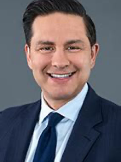 Man in a suit and tie smiling against a gray background.