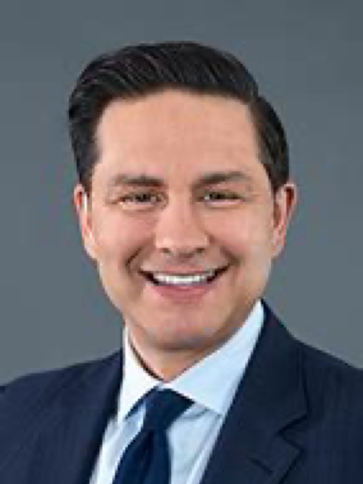 pierre poilievre in a suit and tie smiling against a gray background.